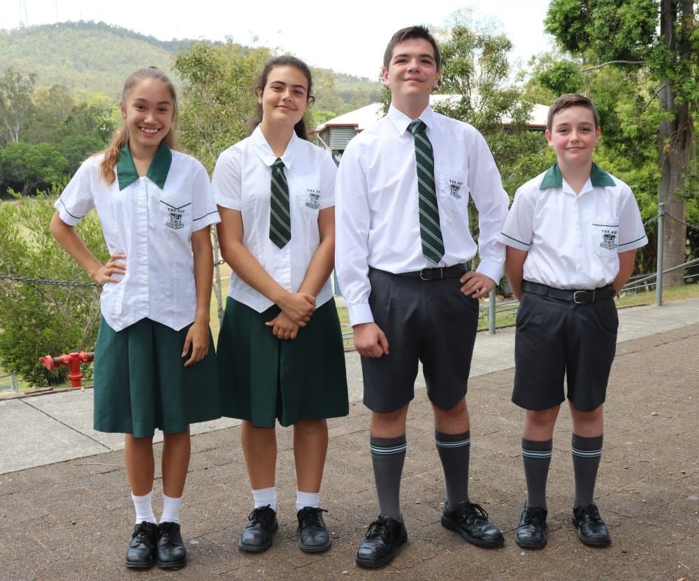 Four students in the summer formal uniform, blouses with green skirts and shirts with grey shorts